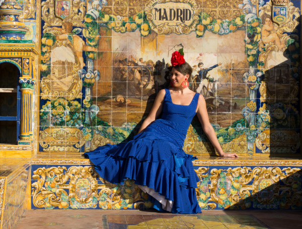Une jeune femme en roble bleu devant des azulejos