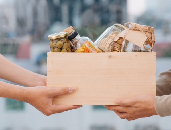 Deux mains qui tiennent un carton avec des vivres à l'intérieur