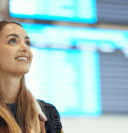 Une femme dans un aéroport devant les tableaux d'affichage